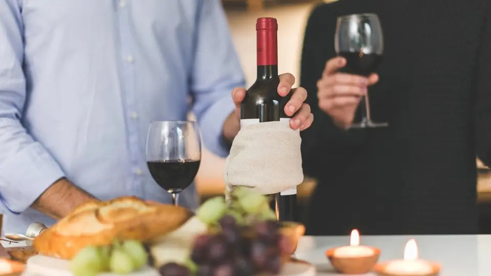 Primo appuntamento a cena: due persone con calici di vino, pane e candele