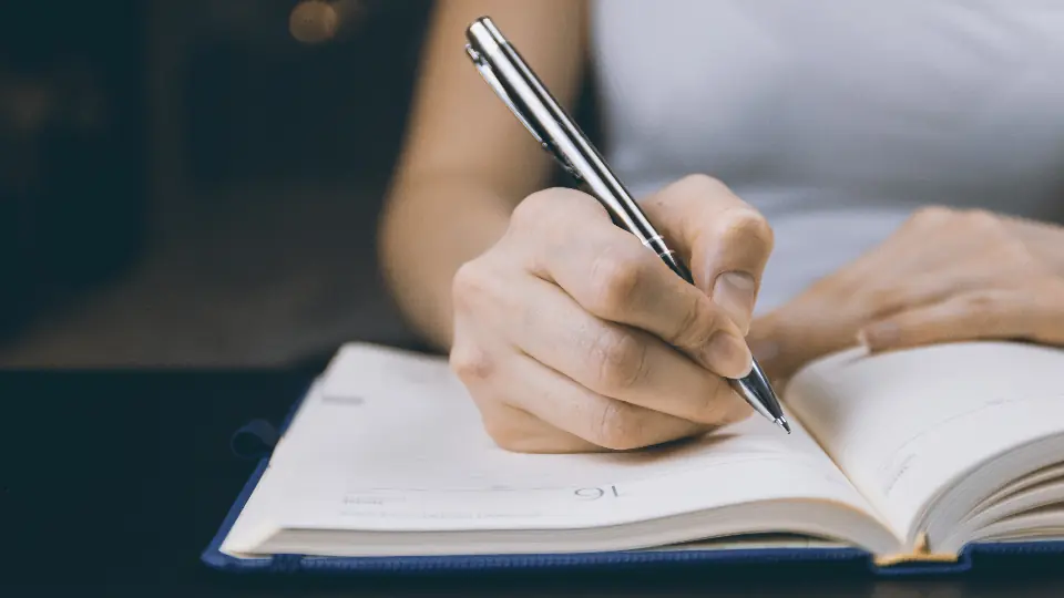 Scrivere il profilo di incontri: una donna scrive con la penna su un'agenda aperta