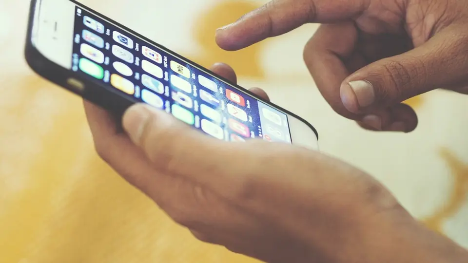 Tinder costo: un dito scorre lo schermo di uno smartphone tenuto in mano