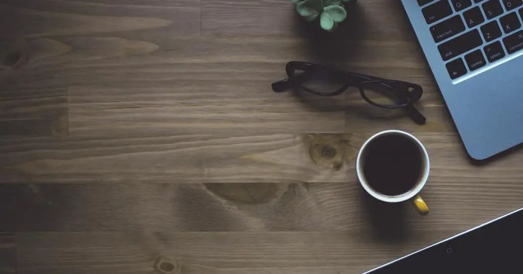 Truffe romantiche online: un portatile, occhiali e una tazza di caffè su una scrivania